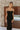 Front view of model wearing the Walk of Fame Midi Dress, which features patterned black velvet, black feathers across the neckline, adjustable thin straps, and a midi mermaid silhouette