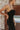 Close-up side view of model wearing the Walk of Fame Midi Dress, which features patterned black velvet, black feathers across the neckline, adjustable thin straps, and a midi mermaid silhouette