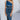 Front view of model wearing the Athena Midi Dress, that has blue satin fabric, a one-shoulder neckline with a braided back strap, a back cutout, and an asymmetrical midi hem.
