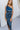 Front view of model wearing the Athena Midi Dress, that has blue satin fabric, a one-shoulder neckline with a braided back strap, a back cutout, and an asymmetrical midi hem.