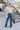 Full body front view of model wearing the Walk The Line Velvet Pants, which feature blue velvet with vertical and diagonal ribbed panels, flared legs, and a high-rise elastic waist.