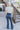 Full body back view of model wearing the Walk The Line Velvet Pants, which feature blue velvet with vertical and diagonal ribbed panels, flared legs, and a high-rise elastic waist.