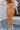 Close-up back view of model wearing the Make It Count Skirt, which features pleated fabric, an elastic waist, and a midi-length. Worn with matching top.