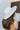 Side view of model's head; model is wearing the New Adventure Has, which is an ivory hat with a wide brim and a band with orange and grey embroidery.