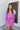 Front view of model wearing the Looking At You Romper, which features textured magenta fabric, a surplice neckline, a tie belt, and long bell sleeves.