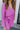Close-up front view of model wearing the Looking At You Romper, which features textured magenta fabric, a surplice neckline, a tie belt, and long bell sleeves.