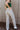 Back view of model wearing the Rooted Denim3: Stella Raw-Hem Flare Jeans, which  feature light brown denim, flared legs with raw-hemlines, and front and back pockets.