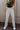 Front view of model wearing the Rooted Denim: Stella Raw-Hem Flare Jeans, which  feature light brown denim, flared legs with raw-hemlines, and front and back pockets.