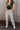 Front view of model wearing the Rooted Denim: Stella Raw-Hem Flare Jeans, which  feature light brown denim, flared legs with raw-hemlines, and front and back pockets.