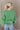Back view of model wearing the On My Own Fringe Sweater, which features green knit fabric with fringe across the chest and sleeves, a round neckline, and long balloon sleeves. 