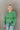Front view of model wearing the On My Own Fringe Sweater, which features green knit fabric with fringe across the chest and sleeves, a round neckline, and long balloon sleeves. 