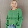 Front view of model wearing the On My Own Fringe Sweater, which features green knit fabric with fringe across the chest and sleeves, a round neckline, and long balloon sleeves. 