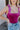 Close-up front view of model wearing the Luna Velvet Bodysuit in Pink, which features magenta velvet fabric, satin tie straps, and a cheeky bottom. Worn with jeans.