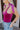 Close-up side view of model wearing the Luna Velvet Bodysuit in Pink, which features magenta velvet fabric, satin tie straps, and a cheeky bottom. Worn with jeans.