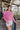 Front view of model wearing the Lucky Me Sweater in Pink, which features a pink knit material, a scoop neck, long sleeves, ruffle detailing at the front sides, and a thick bottom hem