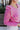 Close-up view of model wearing the Lucky Me Sweater in Pink, which features a pink knit material, a scoop neck, long sleeves, ruffle detailing at the front sides, and a thick bottom hem