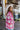 Side view of model wearing the Park City Plaid Shacket, which has a pink and white plaid pattern, a button-up front with tortoise buttons, front chest pockets and corduroy trim. 