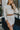 Front view of model wearing the Shine On Sequin Skirt in Champagne, that has beige mesh material with beige sequins, a beige lining, 3/4-length sleeves with shoulder pads, and an exposed back zipper.