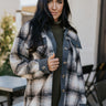 Front view The Rain On Me Shacket features a black, white and tan plaid pattern, a button-up front with tortoise buttons, front chest pockets and grey corduroy trim.