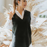 Front view of The Midnight Hour Sweater Vest features black knit fabric, high-low hem, slits on each side, v neckline and sleeveless.