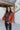 Front view of The Madison Jacket features rust lightweight fabric, cropped waist, grey front zip up, two pockets with zipper closures, high neckline and long balloon sleeves with elastic wrists.