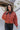 Front view zipped jacket of The Madison Jacket features rust lightweight fabric, cropped waist, grey front zip up, two pockets with zipper closures, high neckline and long balloon sleeves with elastic wrists.