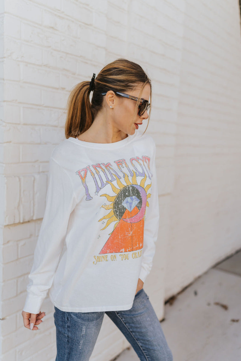Front view of The Pink Floyd Graphic Tee features white cotton fabric, "PINK FLOYD" graphic with a sun, moon, diamond and triangle symbol " Shine on you crazy diamond" and long sleeves