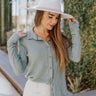 Front view of model wearing the You're With Me Top that has textured sage and light blue knit fabric, a tortoise button up front with a collared neckline, and long sleeves.