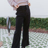 Front view of The Night Out On the Town Pants features black corduroy fabric, two front pockets, front zipper with gold button closure, belt loops and wide leg pant
