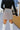 Back view of the Next Steps Skirt that features brown, tan and grey coloring fabric, plaid pattern, silver belt on the waist, overlap detailing, has a lining, and a side zipper for closure.