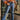 Front view of model wearing the Vervet: Let's Go Cropped Flares that have dark blue denim fabric, distressing, a frayed hem, a high-rise waist, mid flares, two front pockets, two back pockets, and a button and zipper closure