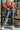 Front view of model wearing the Vervet: Let's Go Cropped Flares that have dark blue denim fabric, distressing, a frayed hem, a high-rise waist, mid flares, two front pockets, two back pockets, and a button and zipper closure