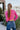Back view of model wearing the Center Of Attention Sweater that has hot pink knit fabric, thick ribbed details, a round neckline, a front triangle hem, a straight hem in the back, and long sleeves