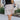 Front view of model wearing the Lexington Corduroy Skirt in Cream that has cream corduroy fabric, ruffle tiered details, a mini length hem, and an elastic waist band