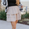 Front view of model wearing the Lexington Corduroy Skirt in Cream that has cream corduroy fabric, ruffle tiered details, a mini length hem, and an elastic waist band