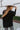 Back view of the Where You've Been Sweater in Black that features black small cable knit fabric, v neckline with cable knit lining, slits on each side of the hem, dropped shoulders and long sleeves with cable knit wrists.