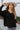 Front view of the Where You've Been Sweater in Black that features black small cable knit fabric, v neckline with cable knit lining, slits on each side of the hem, dropped shoulders and long sleeves with cable knit wrists.