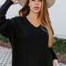 Front view of the Where You've Been Sweater in Black that features black small cable knit fabric, v neckline with cable knit lining, slits on each side of the hem, dropped shoulders and long sleeves with cable knit wrists.