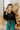 Front view of model wearing the The Late Nights Velvet Top that has  black velvet fabric, a cropped waist, ruched front detailing, a  v neckline, and long sleeves with elastic wrists.
