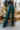 Front view of model wearing the Let's Chat Pants in Emerald that have emerald green fabric, a seam down each front leg, a slight v waistline, a back zipper closure, and wide legs