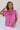 Front view of model wearing the Ashlyn Washed Pink Short Sleeve Top which features washed pink tencel fabric, a scooped hem, a front left chest pocket, a monochrome quarter button-up v-neckline, and short sleeves.