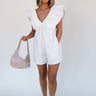 Full body front view of model wearing the Peyton Off White Denim Sleeveless Romper that has off white cotton fabric, two front pockets, a plunge neck, ruffle straps, and a back zipper with a hook closure.