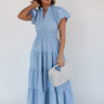 Full body front view of model wearing the Ellie Light Blue Tiered Short Sleeve Midi Dress features light blue fabric, a notched neck with ruffle trim, short puff sleeves, elastic waistband, tiered body, maxi-length, and lining. 