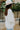 Side view of the In Charge Top In Ivory that features an ivory colored material, a round neck with an adjustable tie closure, a notched neckline, a long sleeve, and a flowy fit.