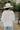 Back view of the In Charge Top In Ivory that features an ivory colored material, a round neck with an adjustable tie closure, a notched neckline, a long sleeve, and a flowy fit.