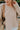 Frontal view of the To The Moon and Back Top that features a brown knit material, a quilted design, a V neckline, long sleeves, side slits, and a flowy fit.