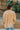 Back view of model wearing the Sloane Corduroy Shacket in Apricot, which features a yellow corduroy material, a collar neckline, a button-up front, a front pocket, and a long cuffed sleeve. 