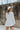 Back  view of model wearing the Love Always Top, which has an ivory colored material, a round neck, a 3/4 button-up front, a long sleeve, front lace detail, a babydoll design, and a flowy fit
