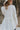 Back view of model wearing the Love Always Top, which has an ivory colored material, a round neck, a 3/4 button-up front, a long sleeve, front lace detail, a babydoll design, and a flowy fit