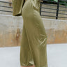 Side view of the All Your Life Pants that features a green satin material, a high-rise fit, a thick elastic waist band with an adjustable tie, and a wide leg fit.